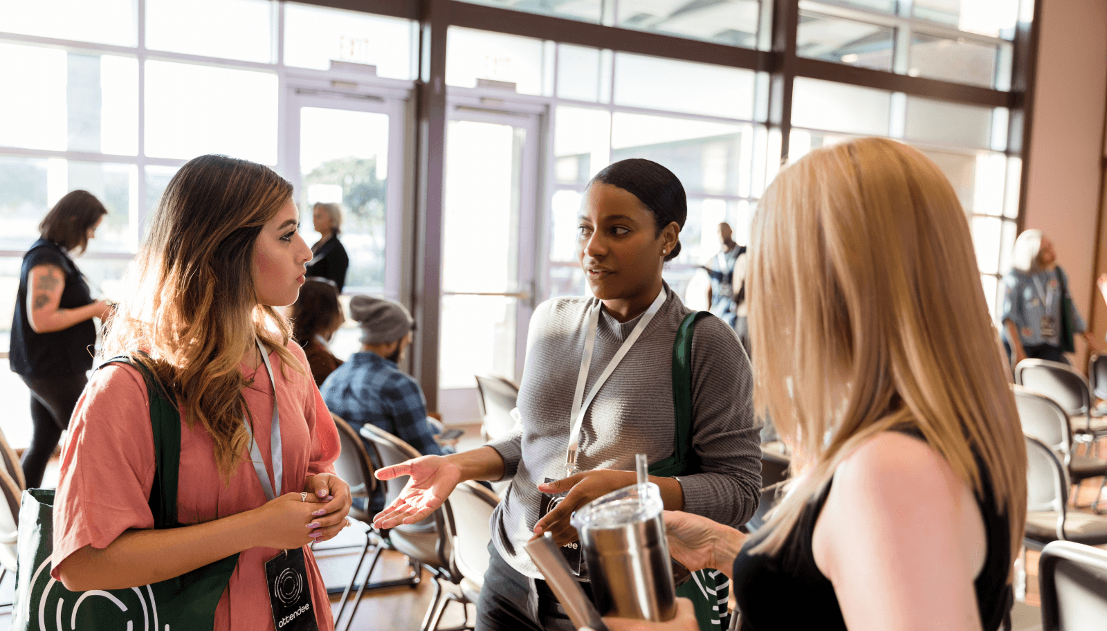 Attendees asking each other for directions in a venue hallway while a session runs nearby