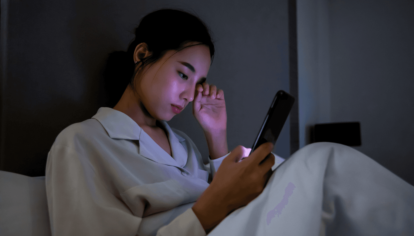 Guest in a hotel room at night messaging a question on their phone