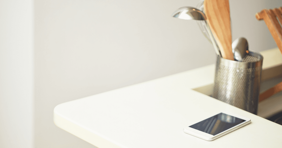 Phone on a kitchen counter showing an unanswered guest question in the evening